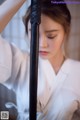 A woman in a white kimono holding a black sword.