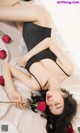 A woman laying on a bed holding a rose.