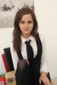 A young woman sitting at a desk wearing a black tie.