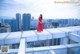 A woman in a red dress standing on a bridge.