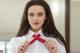 A woman in a white shirt is tying a red tie.