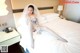 A woman in a wedding dress sitting on a bed.