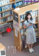 A woman standing in front of a bookshelf holding a book.