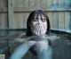 A woman in a hot tub covering her face with her hands.