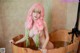 A woman with pink hair sitting in a wooden tub.