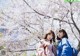 Two young women standing next to each other in front of a tree.