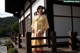 A woman in a yellow kimono standing on a wooden bridge.