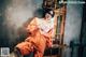 A woman in an orange jumpsuit sitting on a window sill.