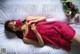 A woman laying on a bed holding a rose.