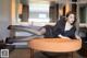 A woman sitting on top of an orange ottoman in a room.