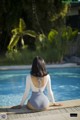 A woman sitting on the edge of a swimming pool.